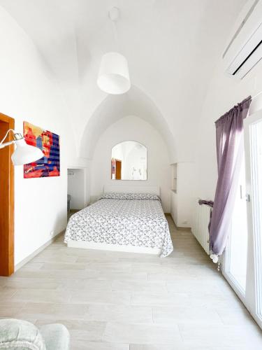 a white bedroom with a bed and a window at Casa Patty nel Vicolo in Ostuni