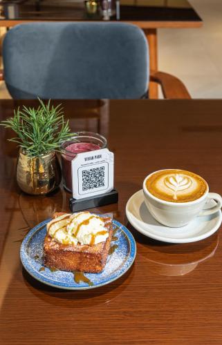 a table with a plate of cake and a cup of coffee at Vivian Park El Raeid Hotel in Riyadh