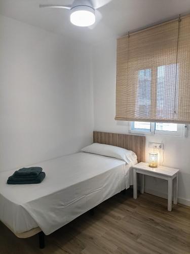 a white bedroom with a bed and a table at Wind Rose Gandia Beach in Playa de Gandia
