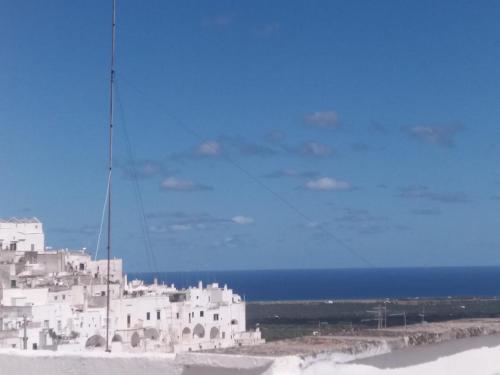 a white building on the beach with the ocean in the background at Casa Patty nel Vicolo in Ostuni