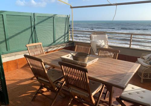 a wooden table and chairs on a balcony with the ocean at Casa Stefania in Anzio