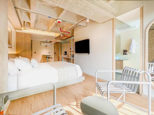 a bedroom with a bed and two chairs at Hotel Once22 in Sabaneta