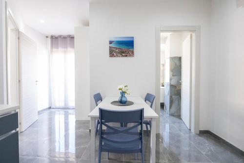 a dining room with a white table and blue chairs at I Due Moli Vibo Marina in Vibo Valentia Marina