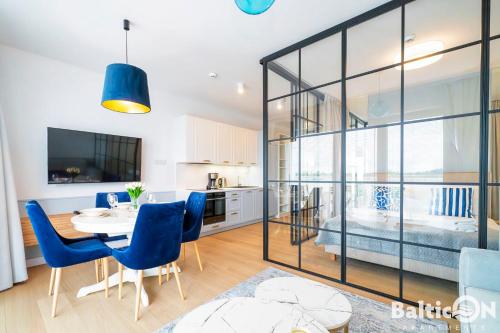 a kitchen and dining room with a table and blue chairs at Apartamenty BalticON Polanki Aqua in Kołobrzeg
