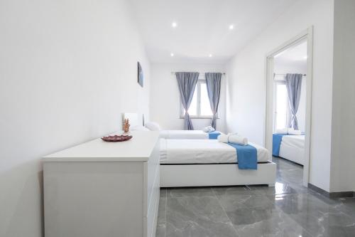 a white bedroom with two beds and a table at I Due Moli Vibo Marina in Vibo Valentia Marina