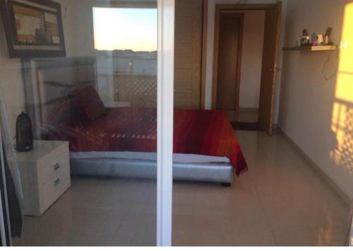 a bedroom with a red bed and a window at Ola Blanca in Dar Hamida