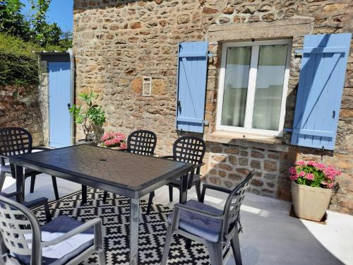 un patio avec une table et des chaises et un bâtiment dans l'établissement Gite de la Levrotiere - Alpes Mancelle, à Saint-Aubin-du-Désert