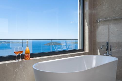 a bath tub in a bathroom with a window and wine glasses at Villa Blue Sunset in Brsečine