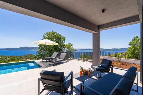 a patio with a table and chairs and a swimming pool at Villa Blue Sunset - Stunning Sea View Luxury Villa with Private Heated Pool in Brsečine