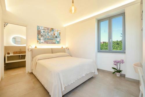 a white bedroom with a bed and a window at Oikos - Charm & Relax Procida in Procida