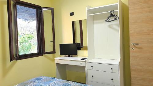 a bedroom with a desk with a computer and a window at Hotel Residence Il Rifugio in Palinuro