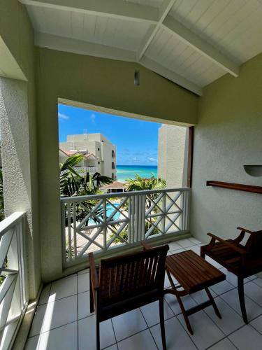 a balcony with two chairs and a view of the ocean at Hôtel Le Roy in Christ Church
