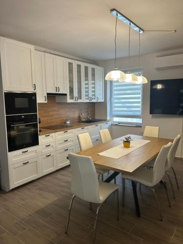 a kitchen with a wooden table and white cabinets at Bodza Vendégház in Badacsonyörs