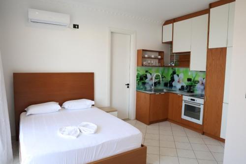 a bedroom with a white bed and a kitchen at A&K Apartments in Sarandë