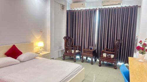 a bedroom with a bed and two chairs and a window at Bao Long Hotel in Ho Chi Minh City