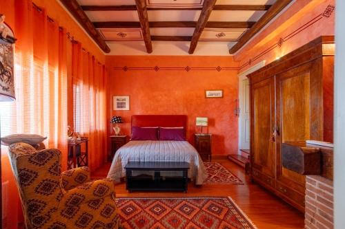 a bedroom with orange walls and a bed and a couch at Casa ER&L in Porto Santo Stefano