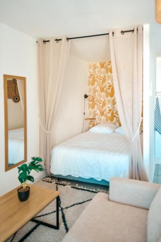 a bedroom with a bed and a mirror and a couch at Studio Le Cosy Consulat - 2 voyageurs in Saint-Denis