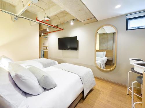 a bedroom with two beds and a mirror at Hotel Once22 in Sabaneta