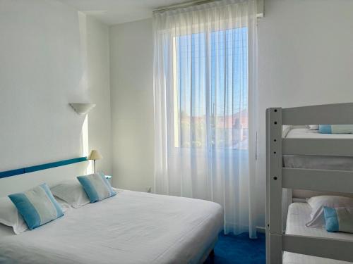 a white bedroom with a bed and a window at Hôtel Orange Marine in Arcachon