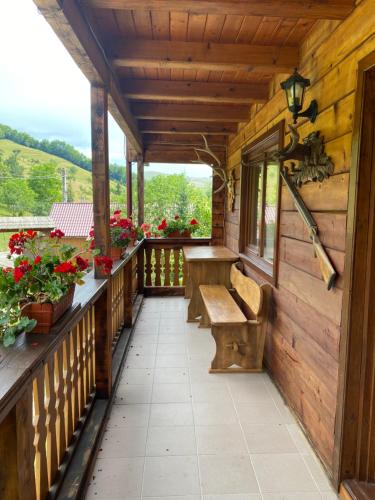 a porch of a cabin with a bench and flowers at Pensiunea Simina in Vişeu de Jos