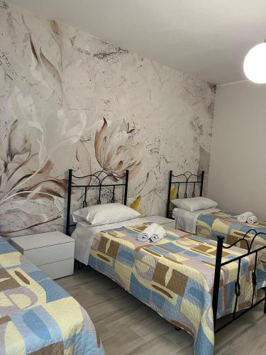 a bedroom with two beds and a wall with a mural at Al Solito Posto Affittacamere in Alianello