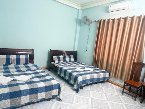 a bedroom with two beds and a window with curtains at Happy Motel in Bien Hoa