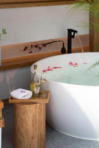 a bath tub with a bottle and two glasses of wine at Chongqing Xiannv Mount Peach Blossom Spring Homest in Wulong