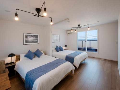 2 bedden in een witte kamer met blauwe kussens bij Town House Suma in Kobe
