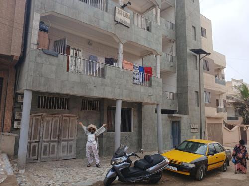 a woman standing in front of a building with her arms up at Casa Djoko in Dakar