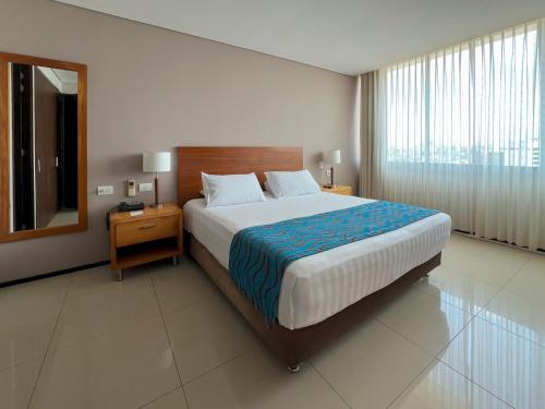 a bedroom with a large bed and a mirror at Estelar Apartamentos Barranquilla in Barranquilla