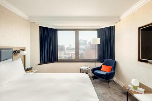a hotel room with a bed and a chair and a window at Hilton London Metropole in London