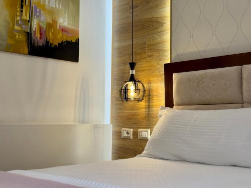 a bedroom with a white bed with a wooden headboard at Triena Rooms in Fier