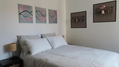 a bedroom with a white bed with three pictures on the wall at Les échappées de Senonches in Senonches
