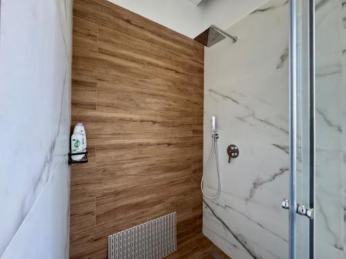 a bathroom with a shower and a wooden wall at Triena Rooms in Fier