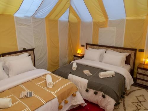 two beds in a room with a tent at Sahara Luxurious Tented in Merzouga