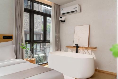 a bedroom with a bed and a chair in front of a window at Chongqing Xiannv Mount Peach Blossom Spring Homest in Wulong