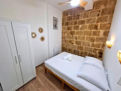 a small bedroom with a white bed and a brick wall at T2 Cosy Clim & WiFi - Ecusson cœur de Montpellier in Montpellier