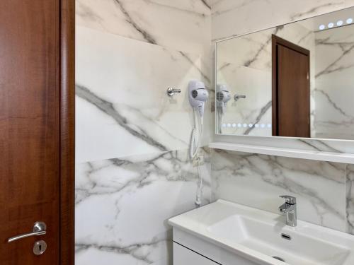 a white bathroom with a sink and a mirror at Triena Rooms in Fier