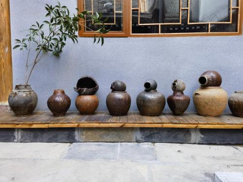 a group of vases sitting on a wooden shelf at 凤凰古城树喜民宿店Shuxi Guesthouse- Fenghuang Ancient Town in Fenghuang