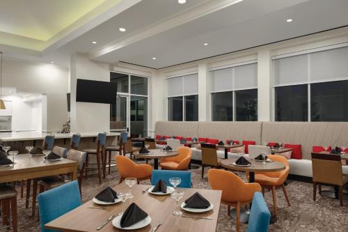 a restaurant with tables and chairs and windows at Hilton Garden Inn Allentown Bethlehem Airport in Allentown