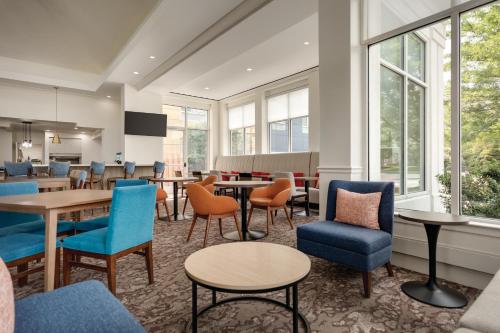 una sala de espera con mesas, sillas y ventanas en Hilton Garden Inn Allentown Bethlehem Airport, en Allentown