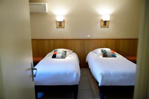 two beds in a hotel room with white sheets at Le Mas Des Aigras - Hôtel & Restaurant de Charme en Provence in Orange