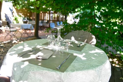 a green and white table with glasses and napkins at Le Mas Des Aigras - Hôtel & Restaurant de Charme en Provence in Orange