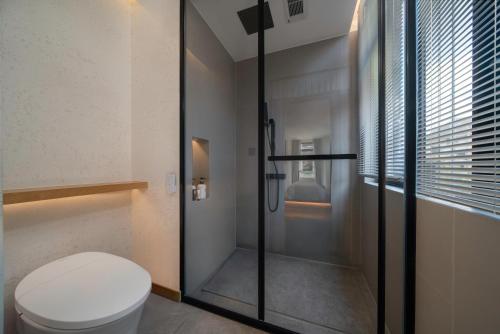 a bathroom with a toilet and a glass shower at Chongqing Xiannv Mount Peach Blossom Spring Homest in Wulong
