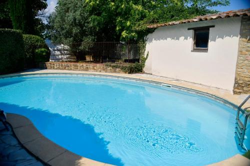 a large blue swimming pool in front of a building at Le Mas Des Aigras - Hôtel & Restaurant de Charme en Provence in Orange