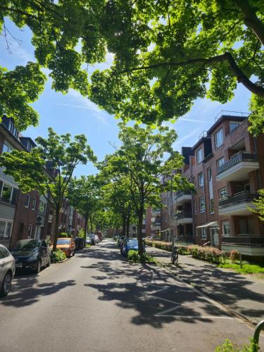 a tree lined street with parked cars and buildings at Stilvolle Maisonette in Neuss - Balkon & Gratis-Parkplatz in Neuss