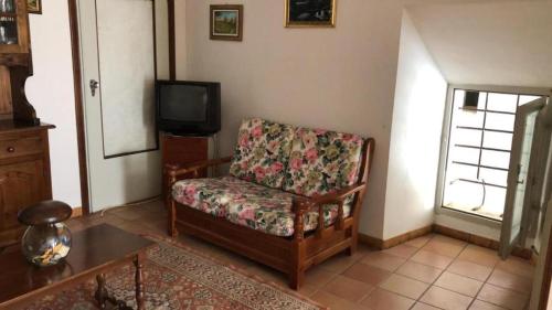 a living room with a chair and a tv at Campo Felice Casa del Lupo in Collimento