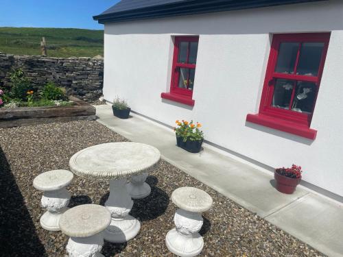 a table and stools in front of a house at Dun Aengus Cottage on the Cliffs of Moher in Liscannor