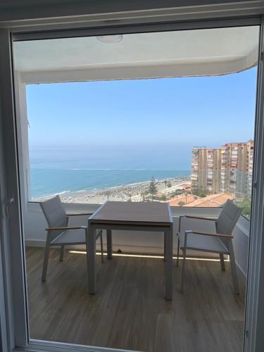 a table and two chairs in a room with a large window at Apartamento Centro Internacional Torrox Costa in Torrox Costa