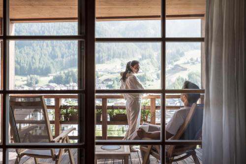 a woman standing on a balcony looking out of a window at Adler Spa Resort Balance in Ortisei